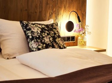 Hotel Gut Edermann Ausschnitt Bett mit dunkler Holzvertäfelung