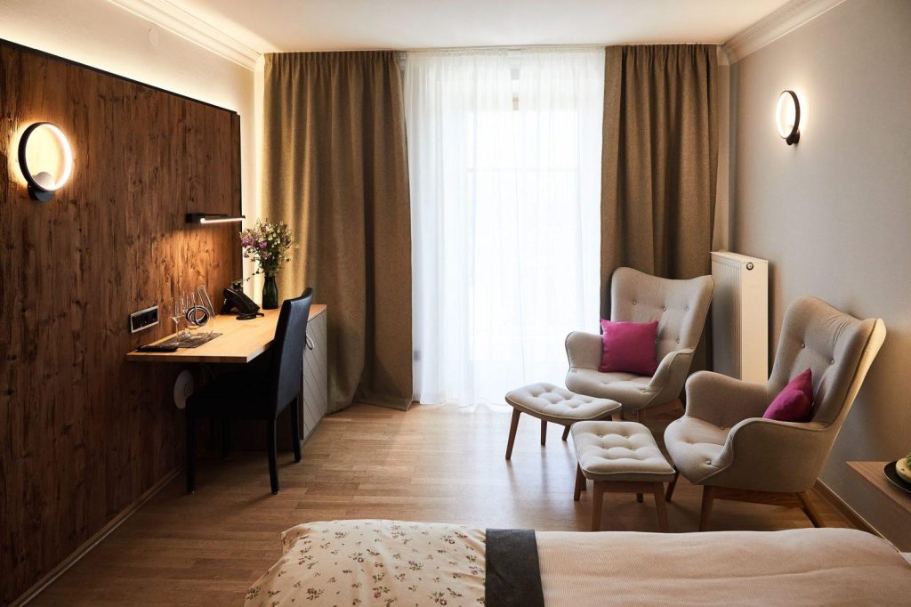 Hotel Gut Edermann Zimmer mit Fenster, Sessel, Bett, Schreibtisch, Wand mit Holzvertäfelung