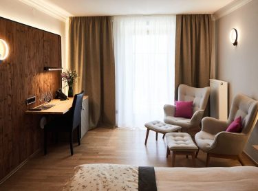 Hotel Gut Edermann Zimmer mit Fenster, Sessel, Bett, Schreibtisch, Wand mit Holzvertäfelung